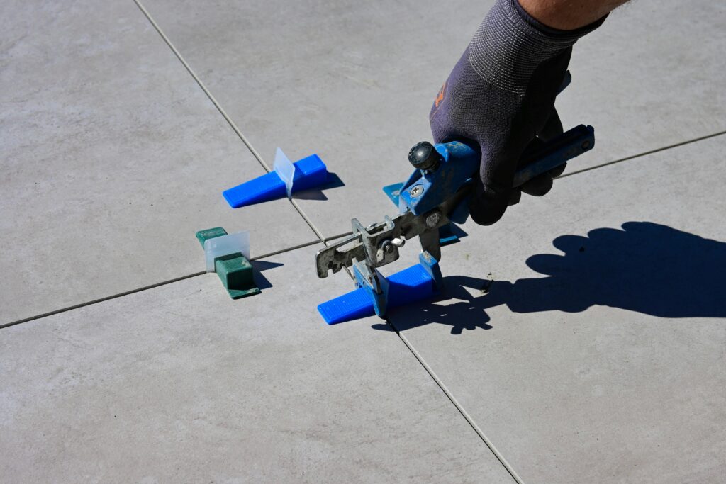 pexels-photo-11806476-11806476 A gloved hand using a leveling tool to install tiles with spacers.